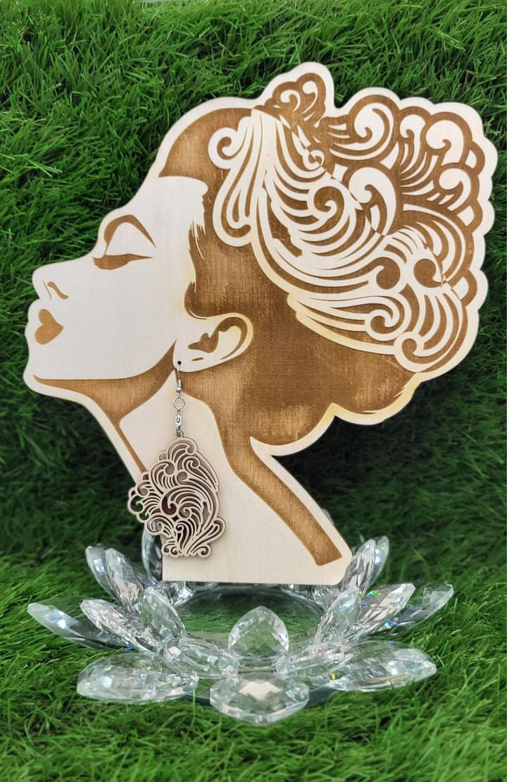 Intricately designed Boujee Stoner Vapor Earrings made from birch wood, hanging from a decorative wooden earring stand shaped like a woman's profile.