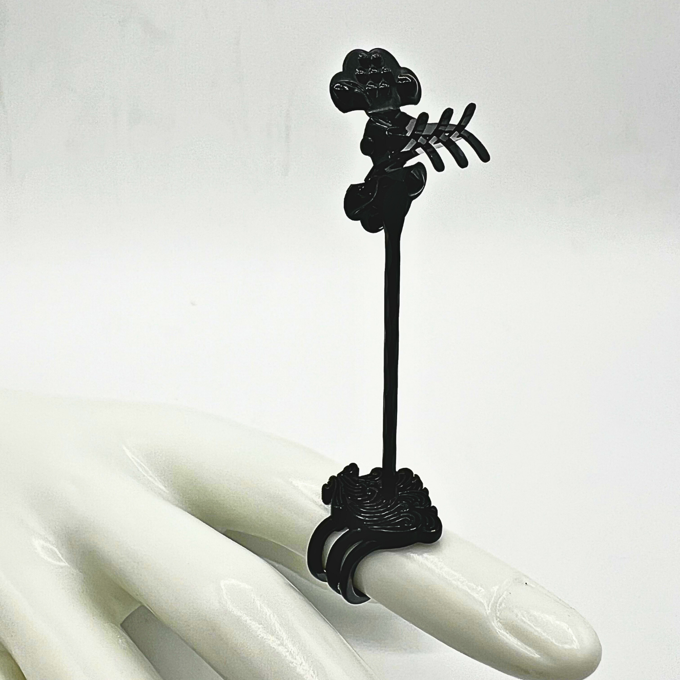 Black decorative item on a white hand with a plain background